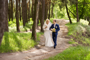 Happy bride and groom walking in forest after their wedding ceremony