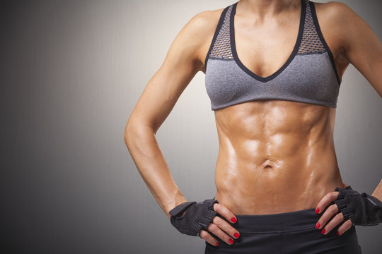 Cropped image of a fitness woman on gray background