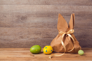 Easter holiday concept with gift bag and eggs decorations over wooden background