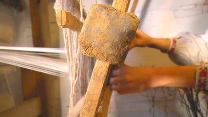 Ancient Weaving Tools A man uses an ancient machine to make fabric.