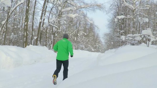 Slow Motion Young Sportsman Running Through Snowy Forest. Training and Exercising Outdoors When Cross Country Running in Inspirational Winter Landscape. Sports Motivation.