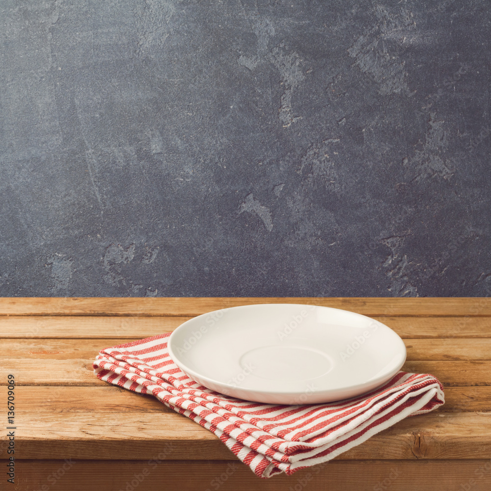 Wall mural Empty white plate on wooden table over blackboard background