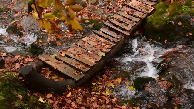  Wooden bridge through autumn river with clean water in the Carpathian mountains.