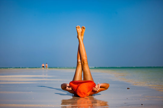 Красивая женщина в шляпе лежит на пляже тропического острова Занзибар.