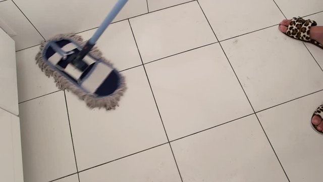 Mop sweeping tile. Dirty white floor. Cleaning product commercial.