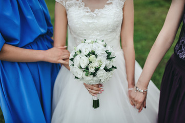 Bride with bouquet holding hands with bridesmaids