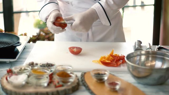 Chef cutting tomato. Cooking board and vegetable pieces. Natural ingredients for vegetarian dish.