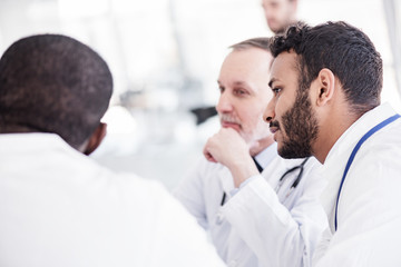 Serene bearded physician hearing colleagues during colloquy