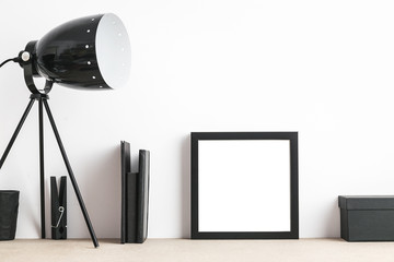 Modern and stylish interior with empty frame, lamp and houseplant. Mock up.