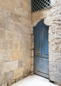 Vintage blue wooden closed door, wooden window with interleaved wooden grid (mashrabiya) and stone bricks wall