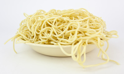 Spaghetti pasta with strands falling over edge of bowl. No sauce. White background.