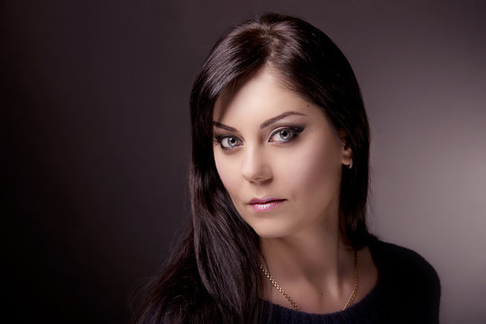 Close-up portrait of brunette with bright makeup on dark background