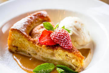 A piece of cheesecake with fresh strawberries, mint and a scoop