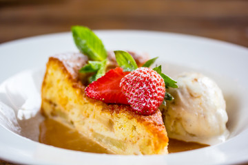 A piece of cheesecake with fresh strawberries, mint and a scoop