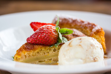 A piece of cheesecake with fresh strawberries, mint and a scoop