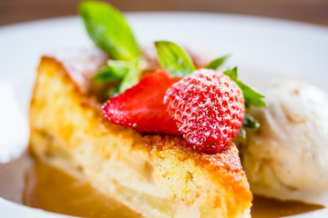 A piece of cheesecake with fresh strawberries, mint and a scoop