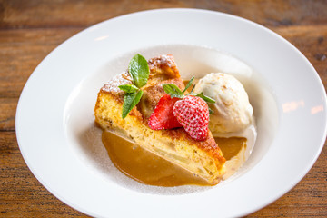 A piece of cheesecake with fresh strawberries, mint and a scoop