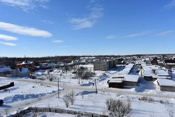 winter city on the background of blue sky; building house covered with snow to the horizon; small clouds