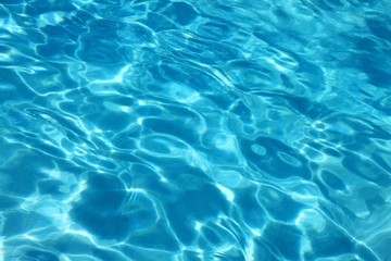 Fototapeta na wymiar Blue water surface viewed from above in outdoor swimming pool, sun reflection, dimply.