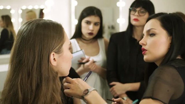 Professional female make-up artist teaching other visagistes to the art of make-up. HD