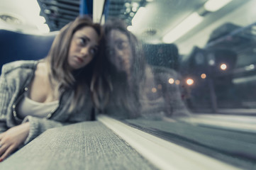 Blur image of a young woman on a train watching at the window.