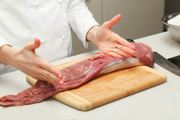 cook cuts a piece of meat