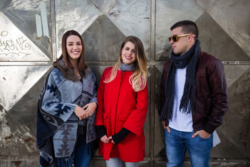 Three happy friends standing and smiling outdoors