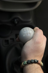 Fototapeta premium Lever manual old school five-speed gearbox and the man's hand that switches transmission. Gear-lever view from above. Handle a manual transmission in a blurry background. five speed manual gear stick