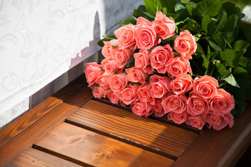 Pink roses are a gift. Flowers lie on a wooden bench.