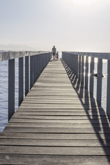 Fototapeta premium Brazil, State of Rio de Janeiro, Paqueta Island, Man and kid on wooden dock during the sunset