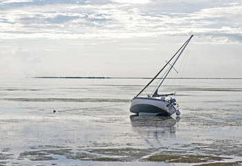 A sailboat stranded in shallow water on an overcast day. Crystal Beach, Florida.