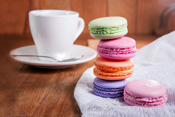 Close up of france dessert colourfull macaroons and cup of tea on wooden table in cafe. Selective focus
