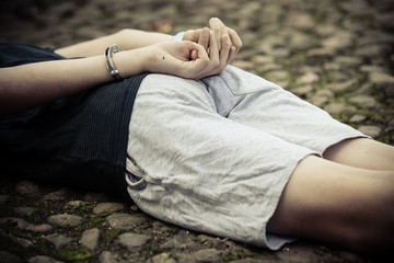 Boy with handcuffed hands lying on the ground