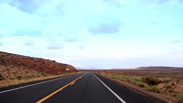 A car drives at Highway, cutting the desert of Arizona with and indescribable beauty. The road travels on painted desert, through a lava field and opens up to the State Mountain and Red Mountain.