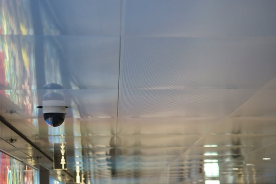 Deckent&auml;felung mit &Uuml;berwachungskamera / Eine abstrakte Deckent&auml;felung aus Metall mit einer rundum &Uuml;berwachungskamera und Hinweisschildern.