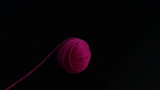One skein of pink knitting yarn appear on black background
