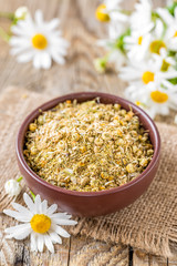 Dried and fresh chamomile flowers and leaves on wooden rustic background, alternative medicine