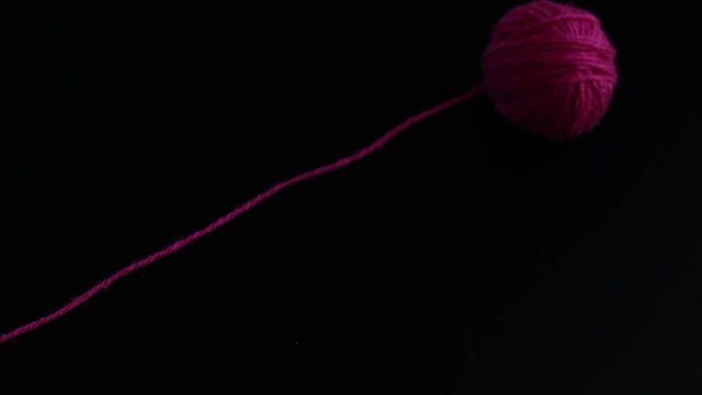 Two skeins of knitting yarn appear and unwound on black background