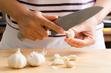 Woman peeling garlic by knife for cooking © nungning20