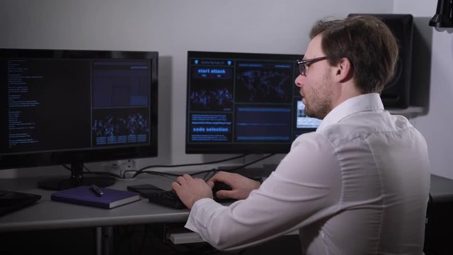 The room with computers. The man using the special software tries to find important information. The person a white shirt and glasses speed enters information in the computer.