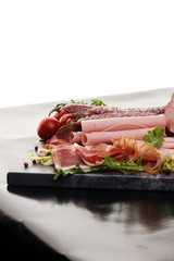 Food tray with delicious salami, pieces of sliced ham, sausage,