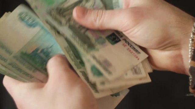 young man's hand counts banknotes Russian rubles