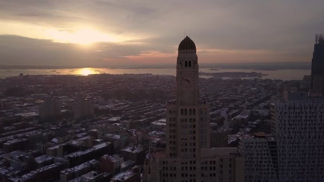 flying past Williamsburgh Savings Bank Tower in Brooklyn towards sunset view