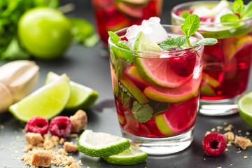 Raspberry mojito cocktail with lime, mint and ice, cold refreshing drink