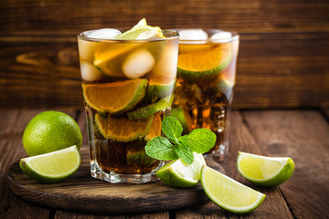 Cuba Libre cocktail with cola, lime and ice in glass, cold longdrink