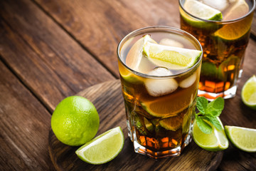 Cuba Libre cocktail with cola, lime and ice in glass, cold longdrink