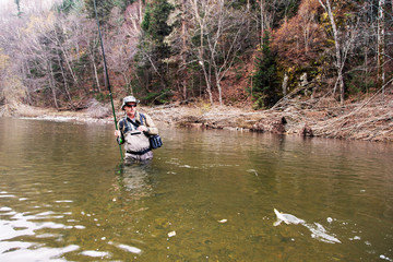 Fototapeta na wymiar Fisherman caught a grayling in a mountain river