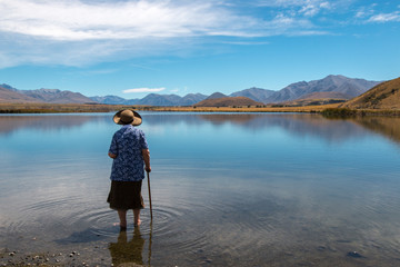 Old lady standing in shallow water of a lake