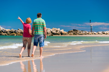Senior couple walking at the beach holding hands of each other