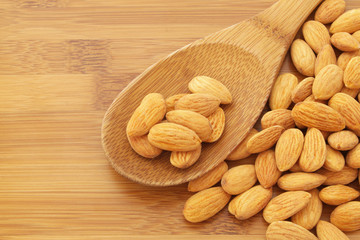 Almonds on wooden background with spoon